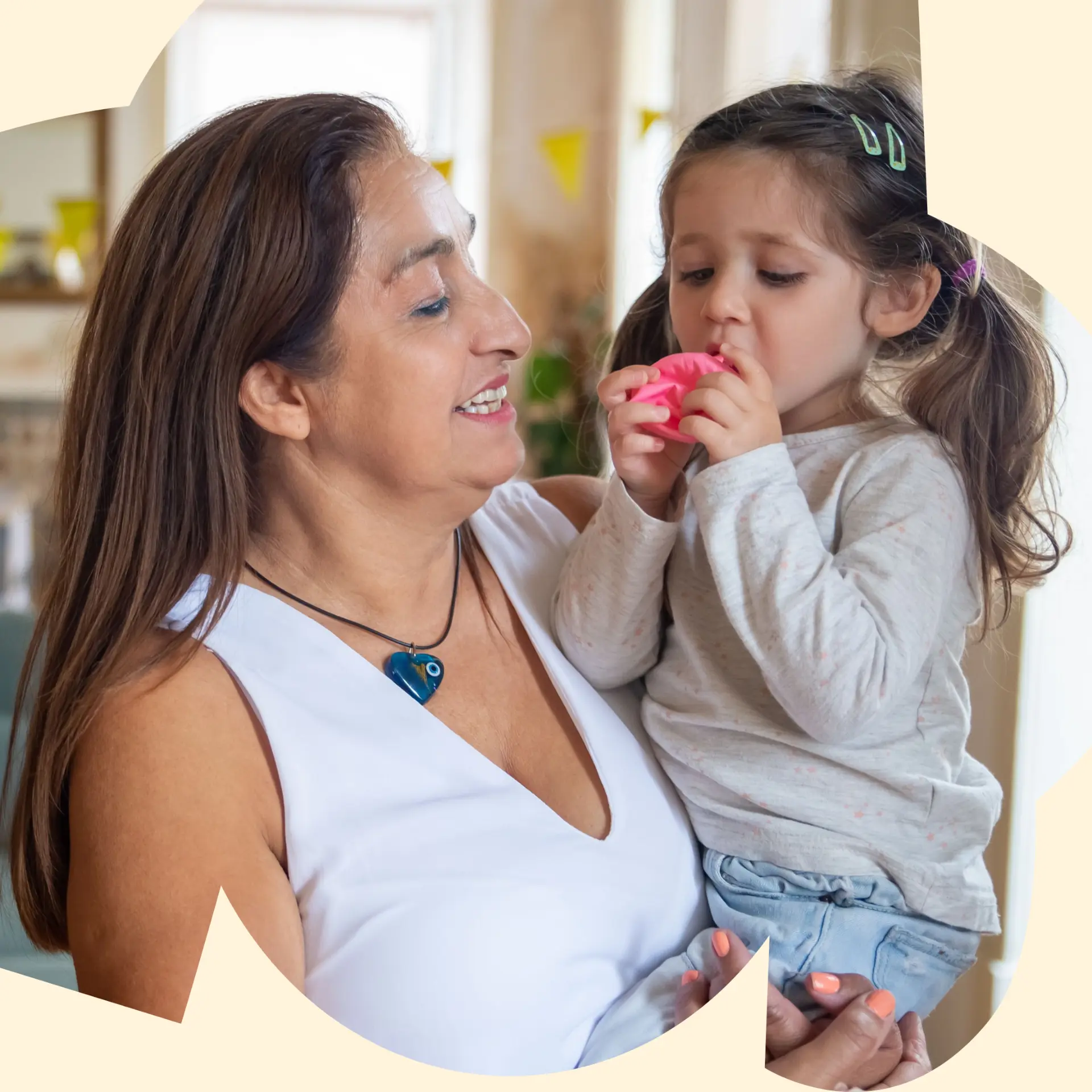 Nanny playing with a smiling toddler in a bright home living room